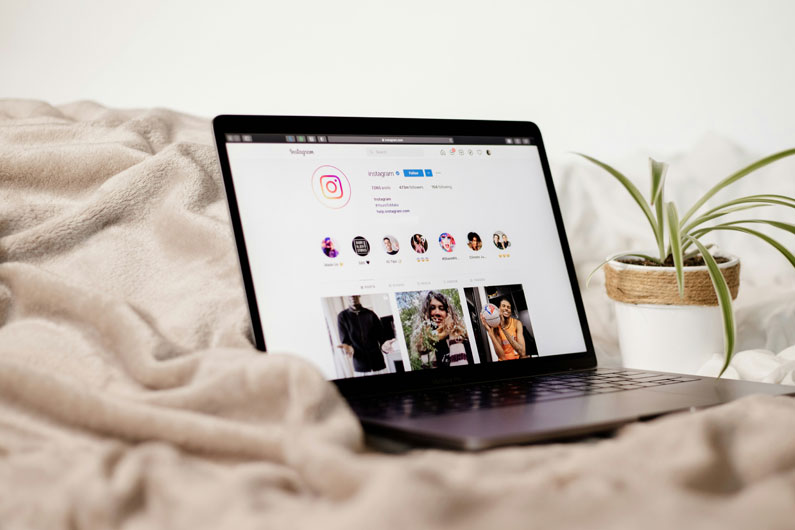 A laptop on a blanket that is open to an Instagram page.