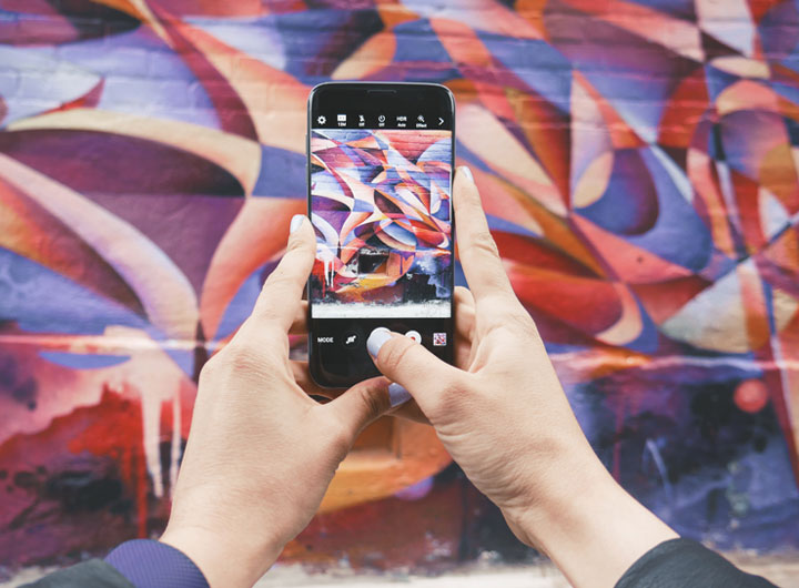 An influencer taking a photo of a wall mural in Kensington Market