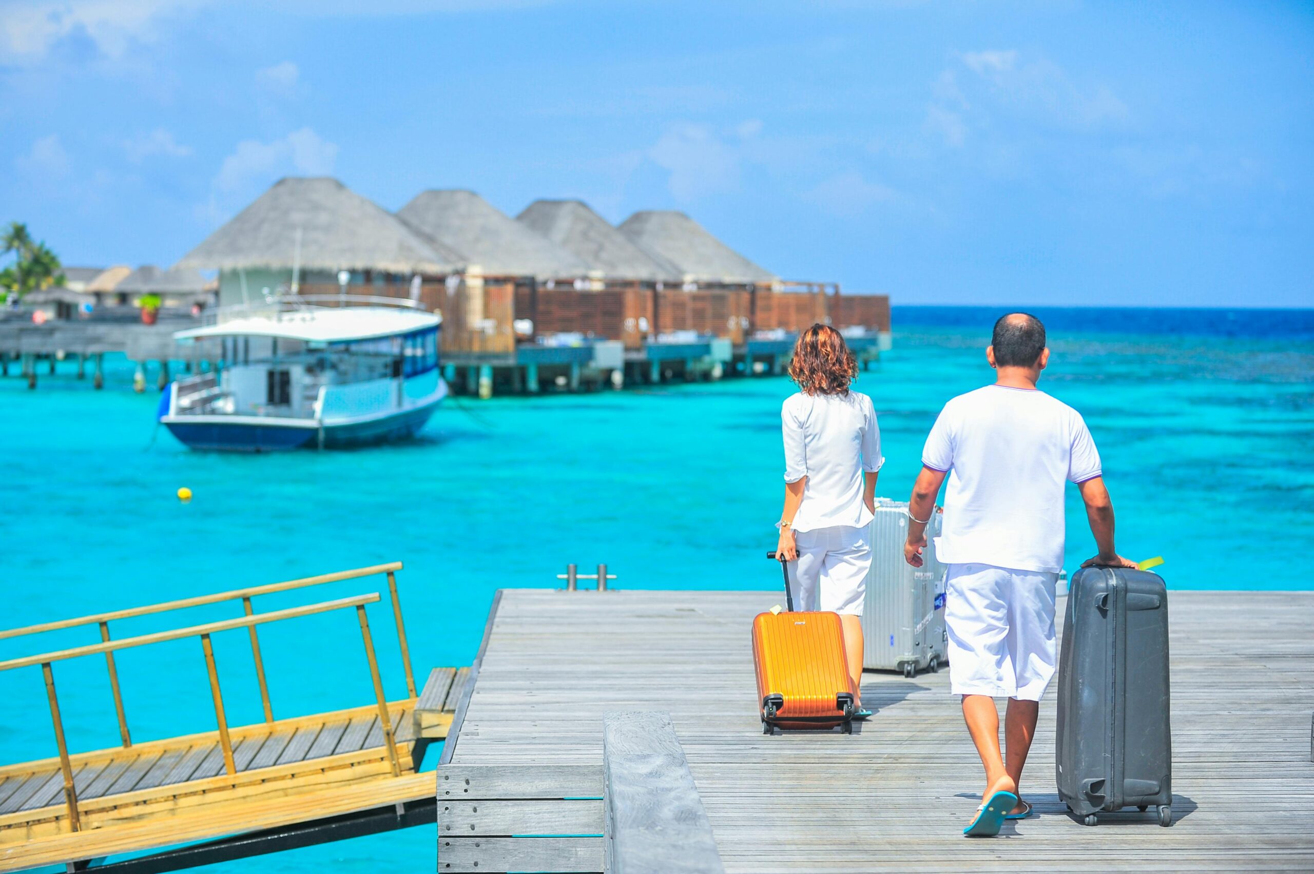 couple carrying luggage to the resort on the beach