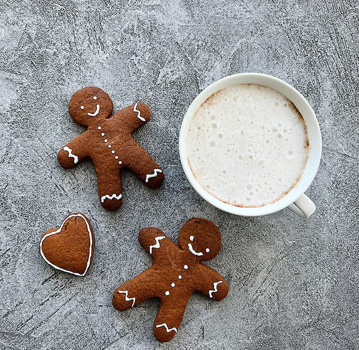 Three gingerbread cookies next to a cup of coffee