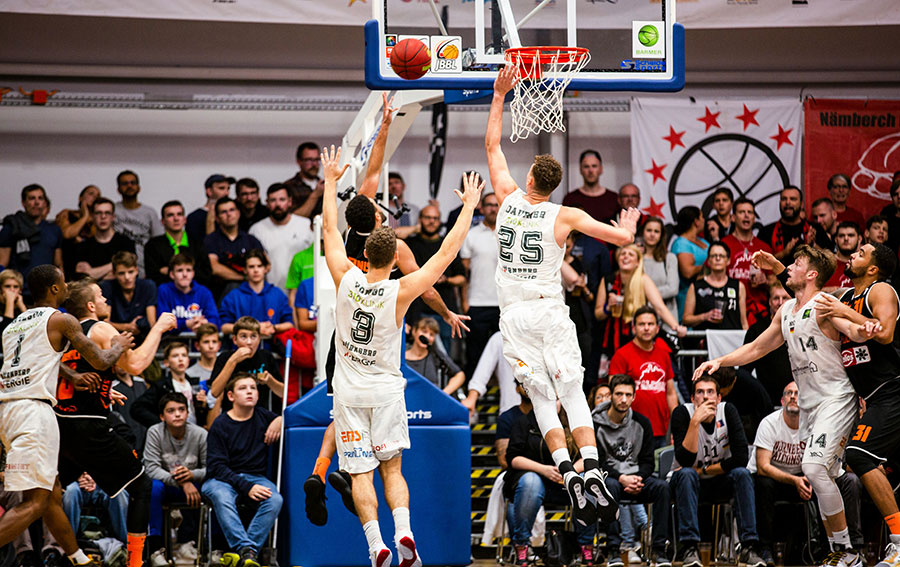 A basketball player trying to sink a basket while the opposing team looks to defend.