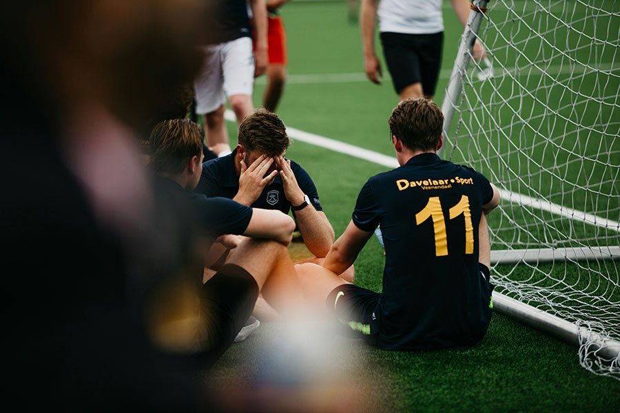 Soccer players behind the net looking defeated.