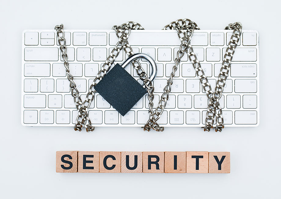 Cyber safety concept with chain and padlock on keyboard, wooden cubes on white background.